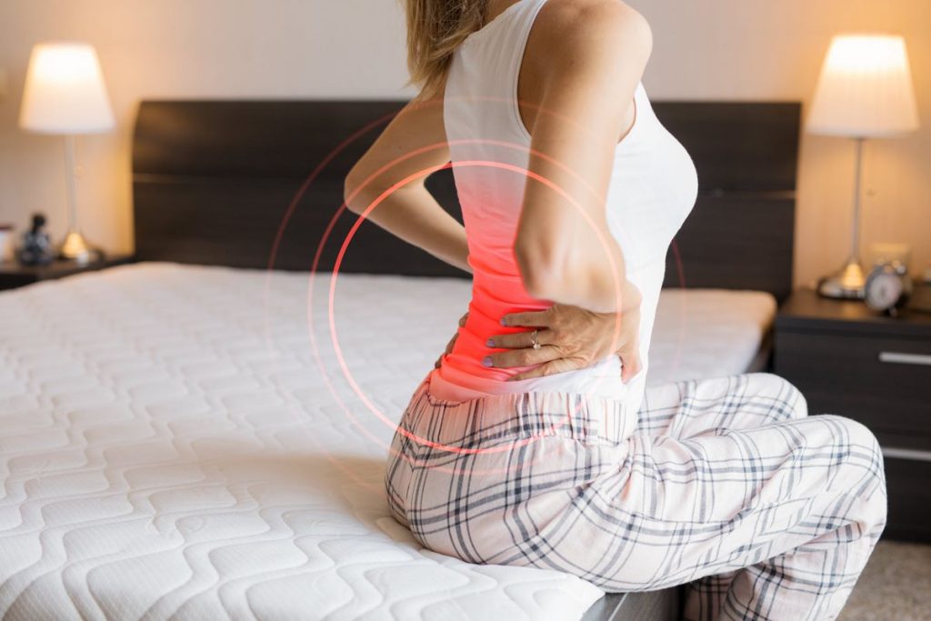 Female experiencing back pain from mattress, highlighting poor sleep support or old bedding.