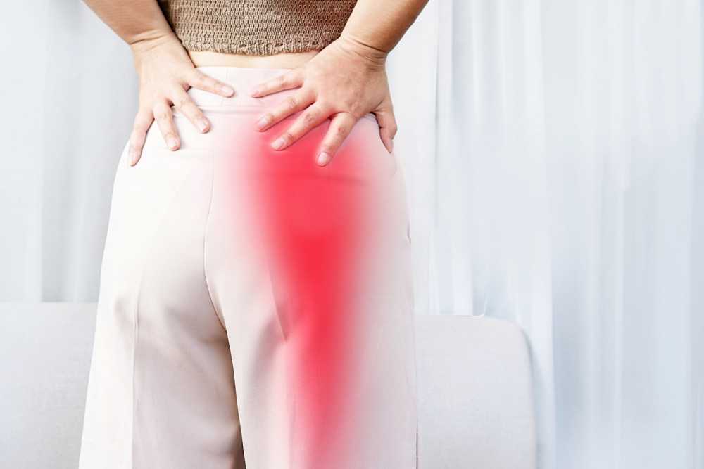 Woman with sciatica pain touching lower back and hip, highlighting common sciatic nerve symptoms.